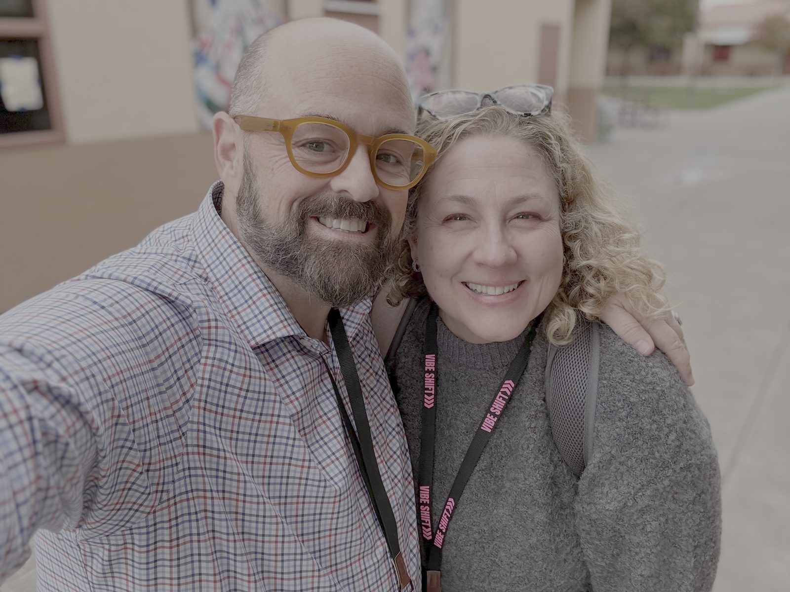 Two Vibe Shift 2025 attendees in pink lanyards taking a selfie outside the Sacramento school venue