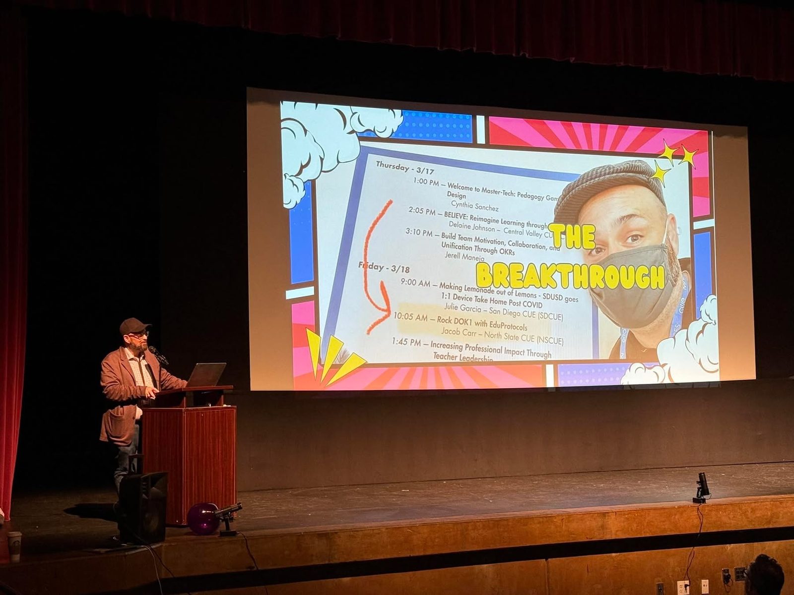 A Vibe Shift 2025 speaker on stage presenting a comic-book-style "Breakthrough" keynote slide with a session schedule projected behind