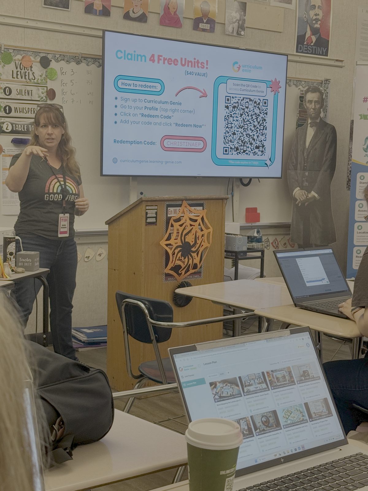 A Vibe Shift 2025 presenter in a "Good Vibes" shirt walking attendees through a Curriculum Genie redemption code displayed on the classroom screen