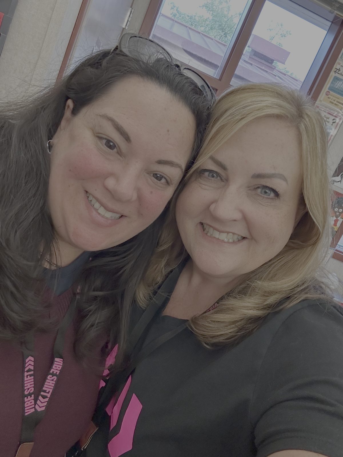 Two Vibe Shift 2025 attendees taking a close-up selfie wearing pink Vibe Shift lanyards inside the conference venue